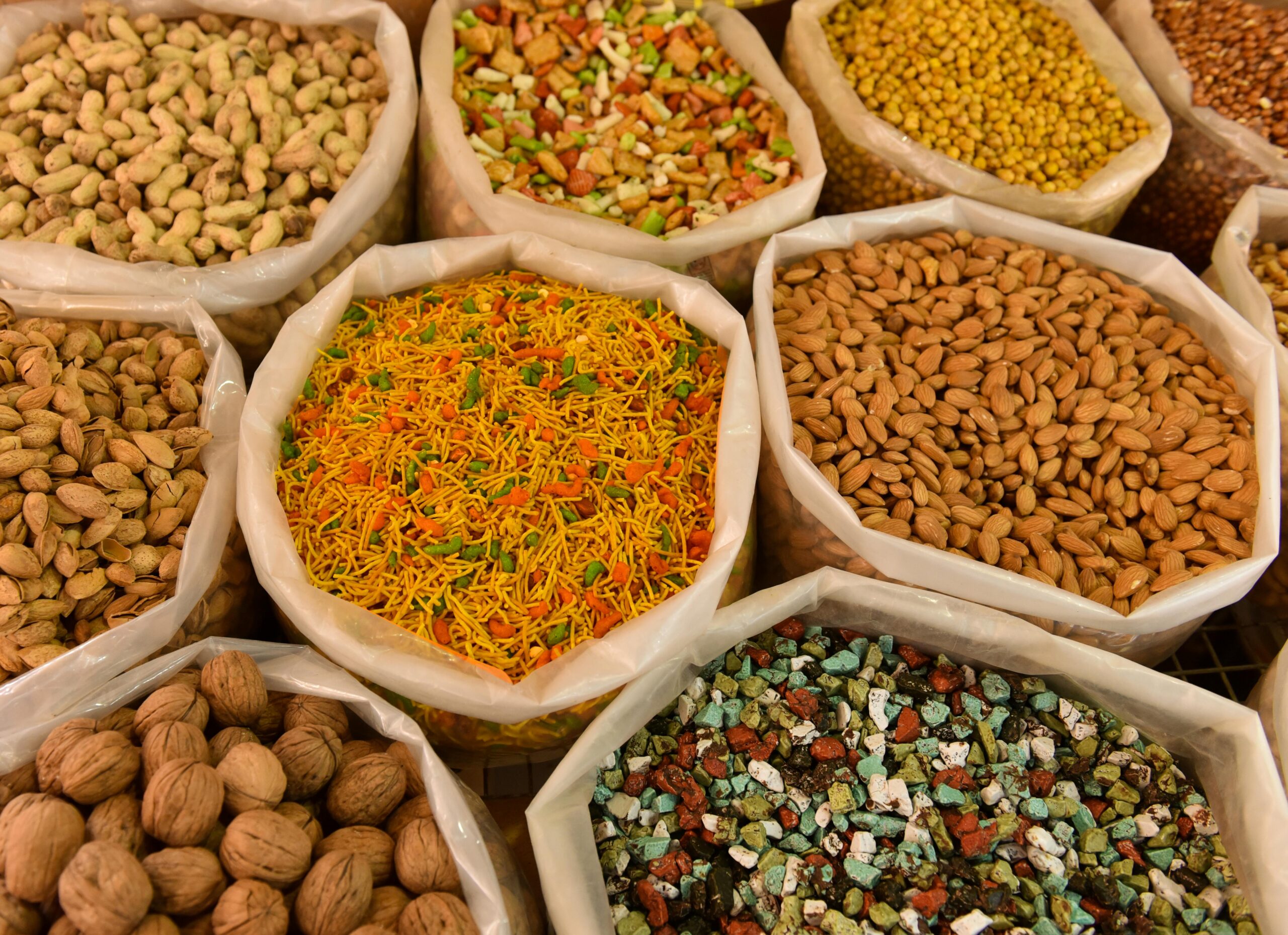 Variety of nuts and spices displayed in bags, showcasing colorful and diverse food options.